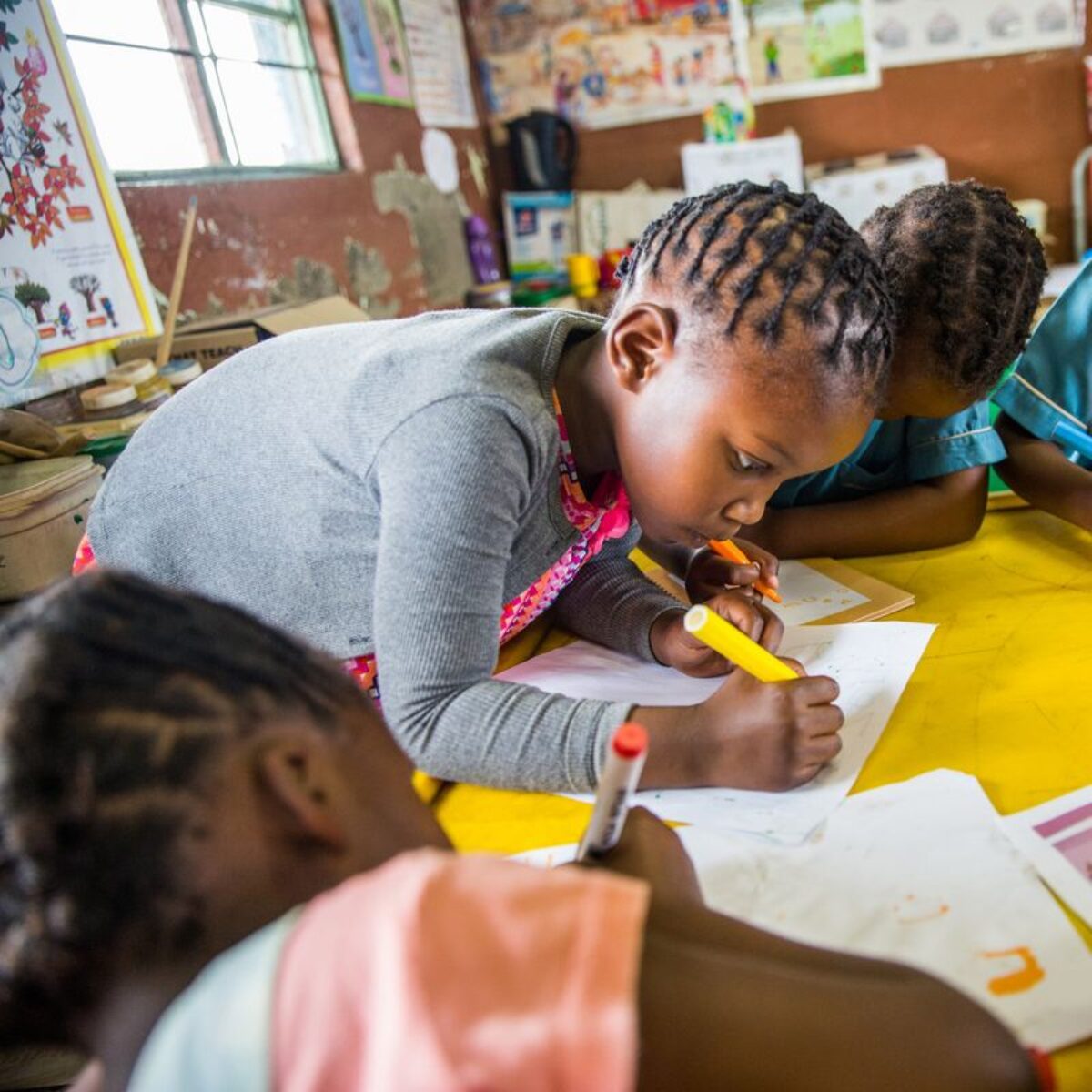 Schoolgirls work around a table in a classroom